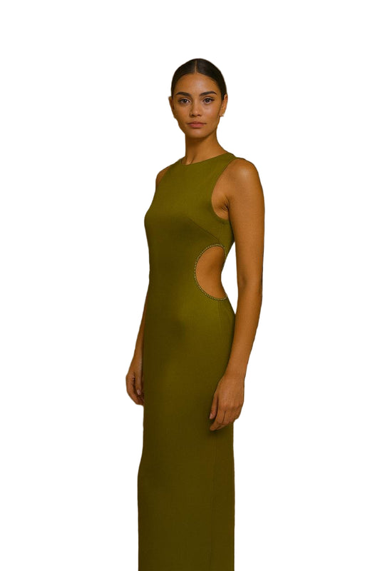 Woman in a green evening gown with cut-out design standing in an elegant indoor setting.