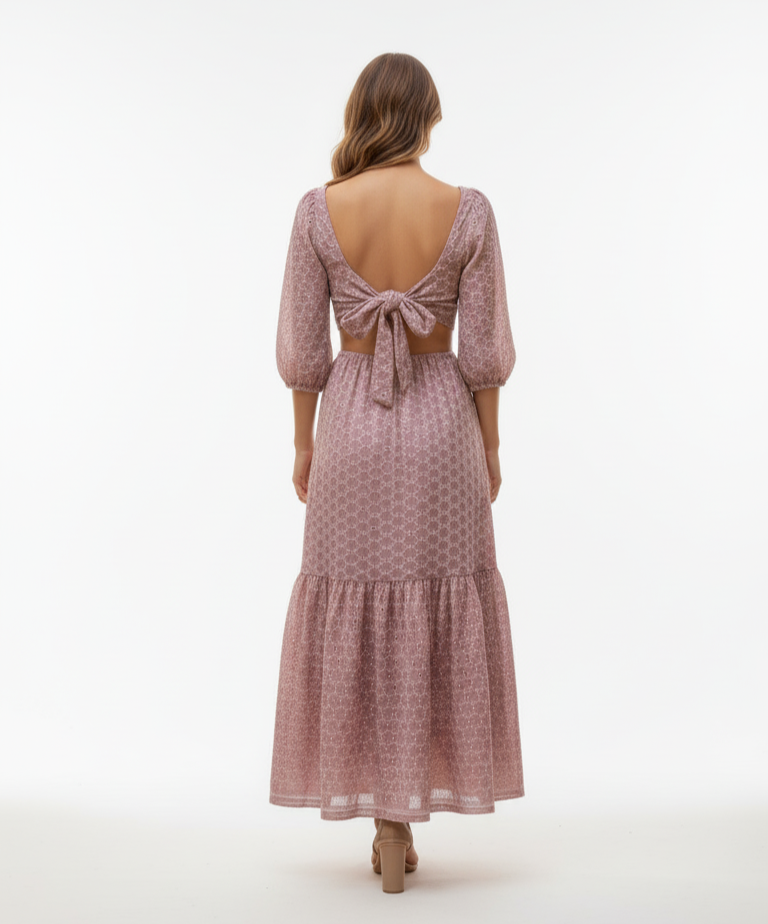 Woman wearing a pink patterned dress with open back on a white background