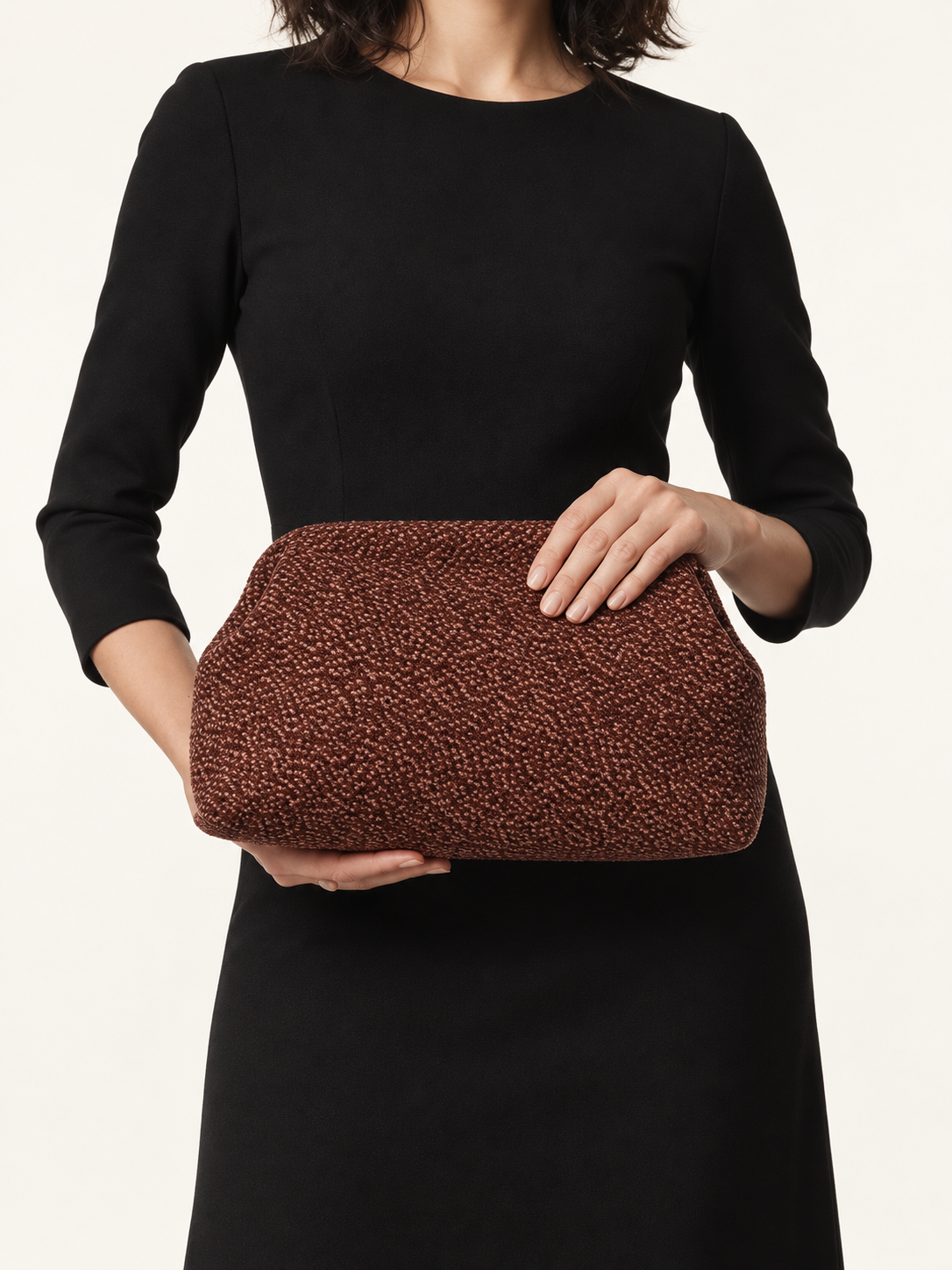 Brown Textured Clutch with rounded corners, carried by a model in a black dress