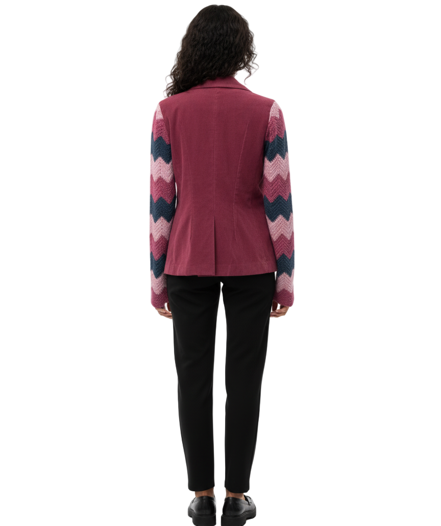 Person wearing a pink cardigan with a colorful pattern on sleeves against a white background