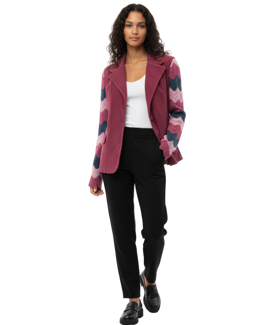 Woman wearing a patterned coat over a white top and black pants on a white background