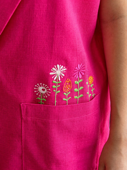 Close-up of multicoloured flower embroidery and woven fuchsia fabric above the vest pocket