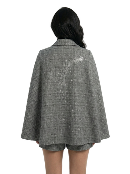 Person wearing a gray cape with decorative elements on a white background