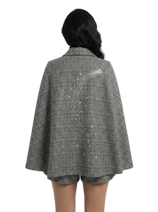 Person wearing a gray cape with decorative elements on a white background