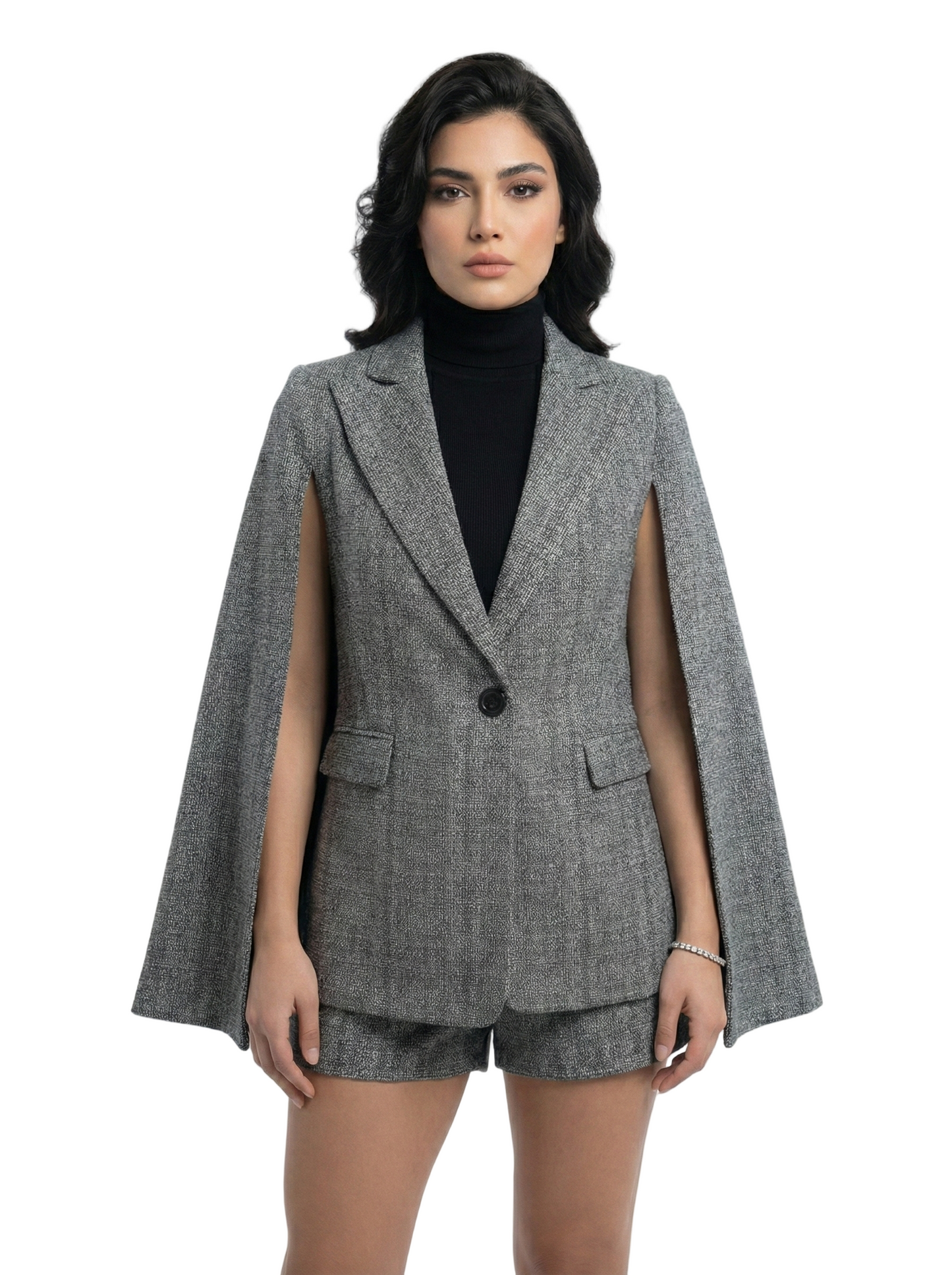 Woman wearing a gray cape blazer over a black turtleneck on a white background