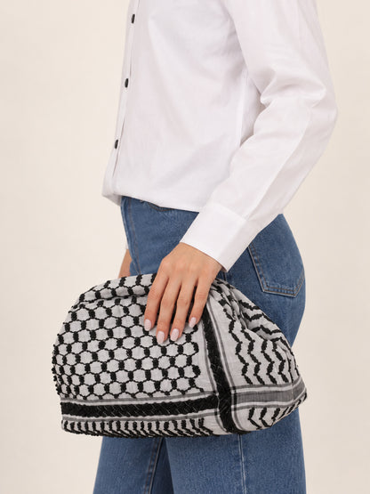 Black and white keffiyeh fabric clutch with bead detailing, fully visible at the model’s hip