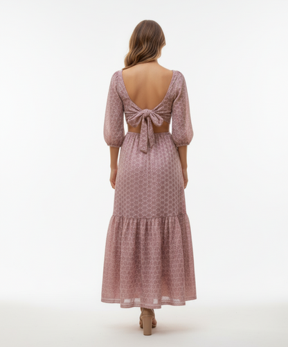 Woman wearing a pink patterned dress with open back on a white background