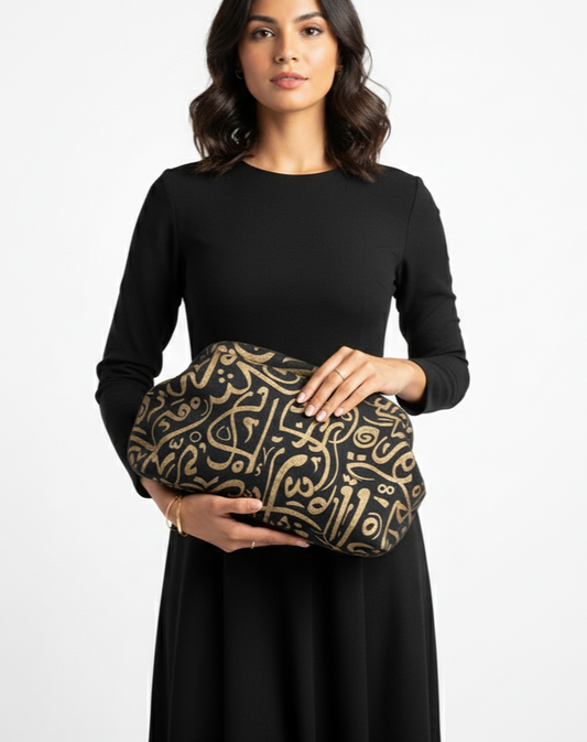 Woman holding a black clutch with gold patterns against a white background