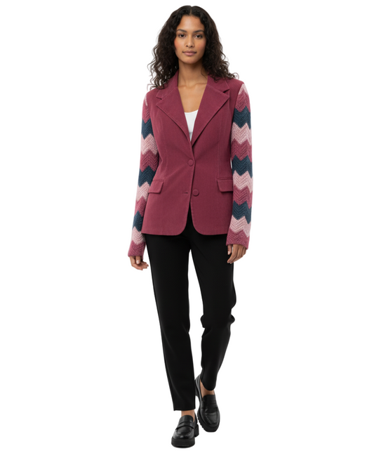 Woman wearing a pink blazer with a colorful patterned sleeve on a white background
