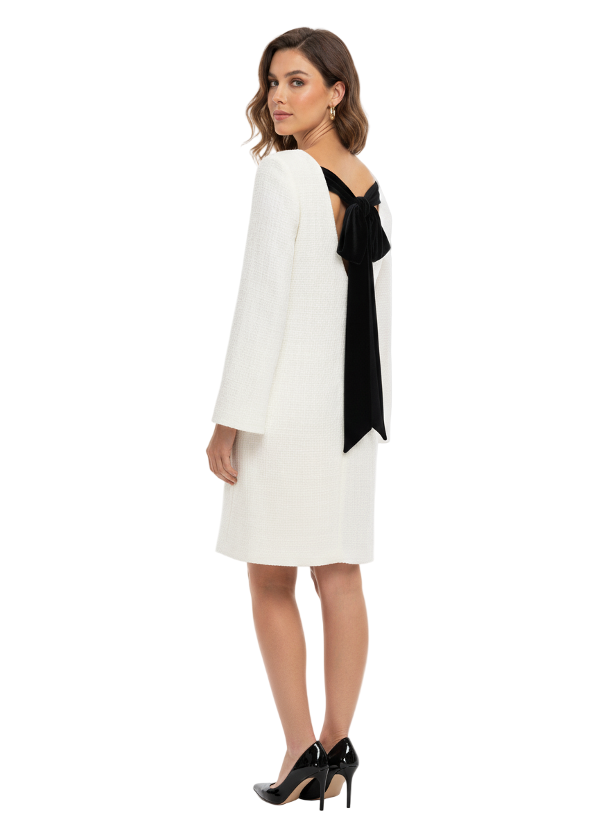 Woman wearing a white dress with a black bow detail on a white background